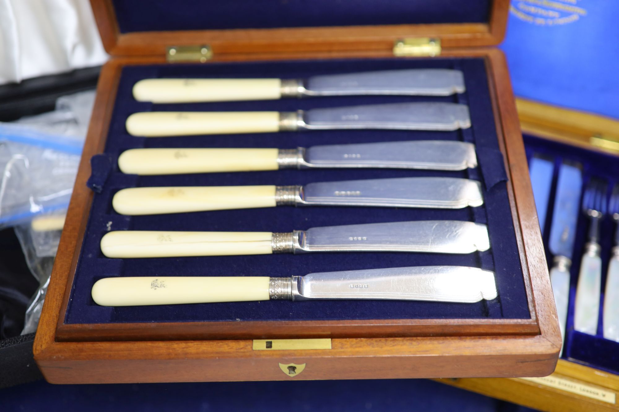 A cased set of silver dessert knives and forks and two other boxes